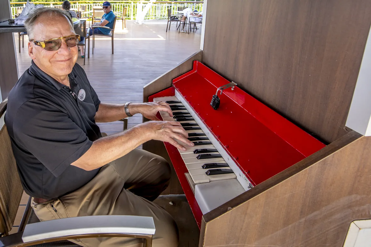 A crew member plays the American Queen's steam calliope, its red-lined keyboard open on the deck